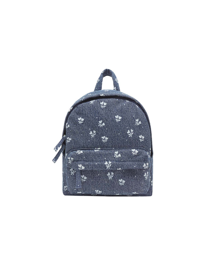 Presenting the mini backpack in heart ditsy by rylee + cru: a small indigo denim backpack featuring a charming white floral and heart ditsy print, complete with a front zipper pocket and top handle, displayed against a plain white background.