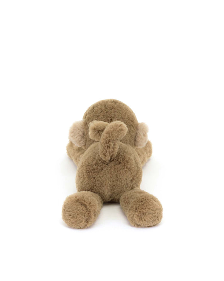 The Jellycat smudge monkey tiny, plush and fluffy, lies on its stomach with legs spread wide, set against a pristine white background.