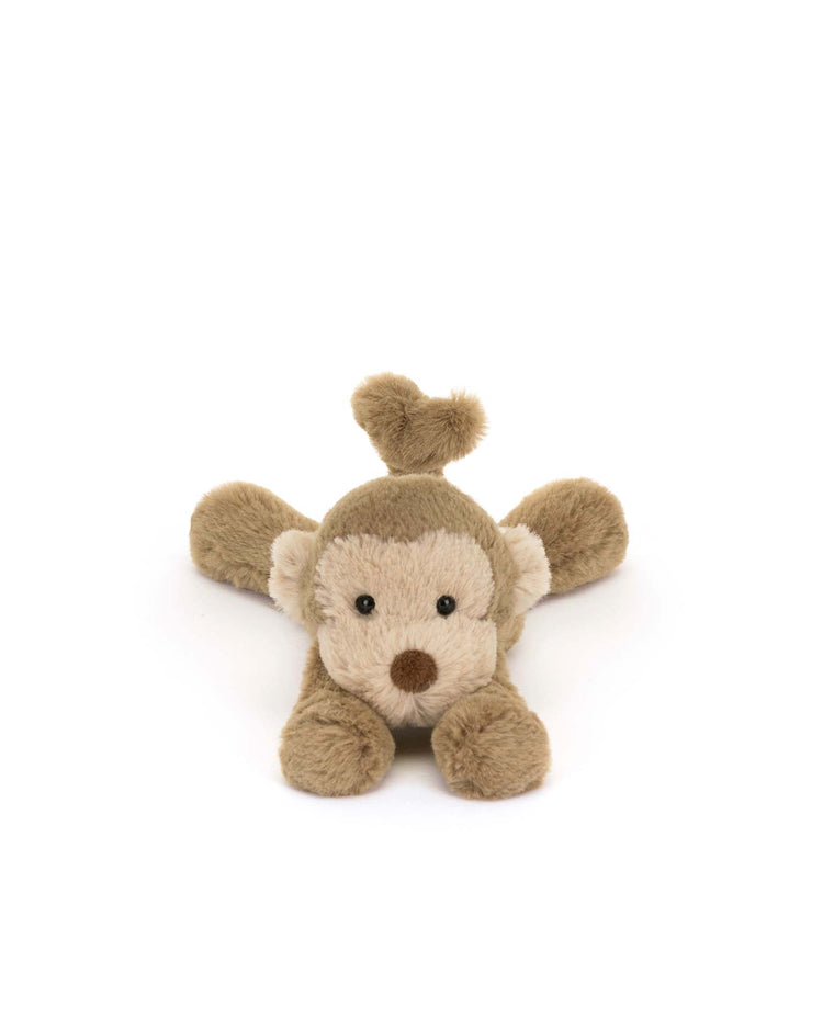 The "smudge monkey tiny" by Jellycat is an adorable fluffy friend, featuring a small tail and lying face forward on a plain white background.