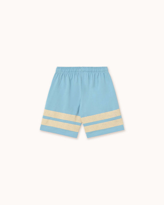 The dusty blue "stripes logo short" from Tiny Cottons features two beige horizontal stripes near the bottom of each leg. Made from organic cotton, it has an elastic waistband and reflects Tiny Cottons' distinctive style, showcased against a plain backdrop.