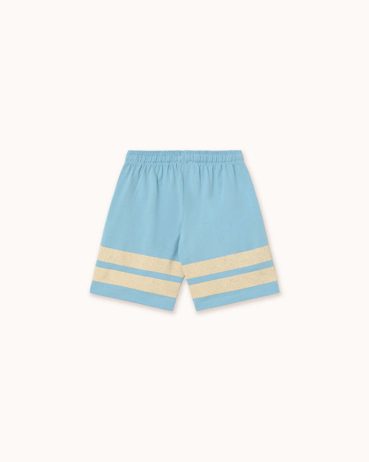 The dusty blue "stripes logo short" from Tiny Cottons features two beige horizontal stripes near the bottom of each leg. Made from organic cotton, it has an elastic waistband and reflects Tiny Cottons' distinctive style, showcased against a plain backdrop.