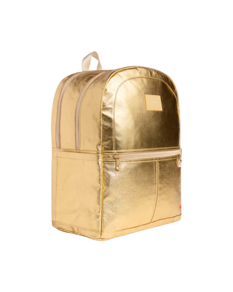 A shiny gold Kane Large Double Pocket Backpack from STATE Bags, featuring a front zipper pocket, a top handle, and a rectangular label on the front—photographed against a white background—makes the perfect standout school backpack.