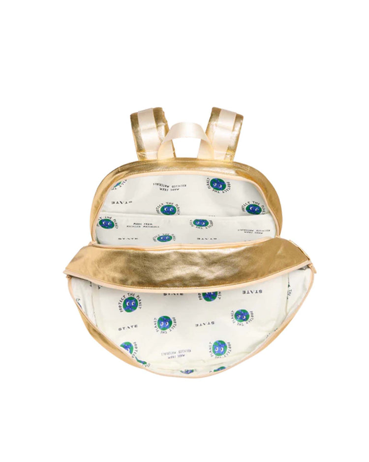 A gold Kane Large Double Pocket Backpack by STATE Bags is shown open, revealing both compartments and a cream-colored interior lining with a blue and green circular pattern and repeating text. The school backpack features gold straps.
