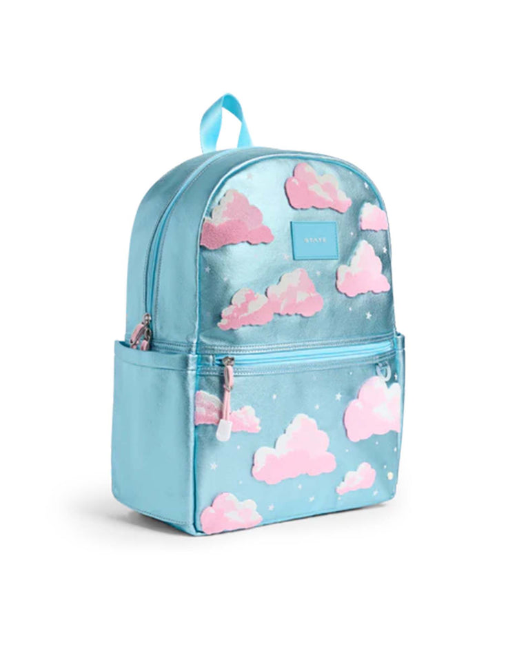 The Kane Backpack in Clouds from STATE Bags features a shiny light blue finish with playful pink cloud designs, white stars, and a front zipper pocket. This stylish school backpack is also equipped with side pockets and a convenient top carry handle.