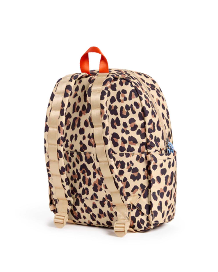 A STATE Bags Kane backpack in leopard print, shown from the back with beige adjustable straps, a red carry handle, side pockets, and a beige and black leopard pattern.