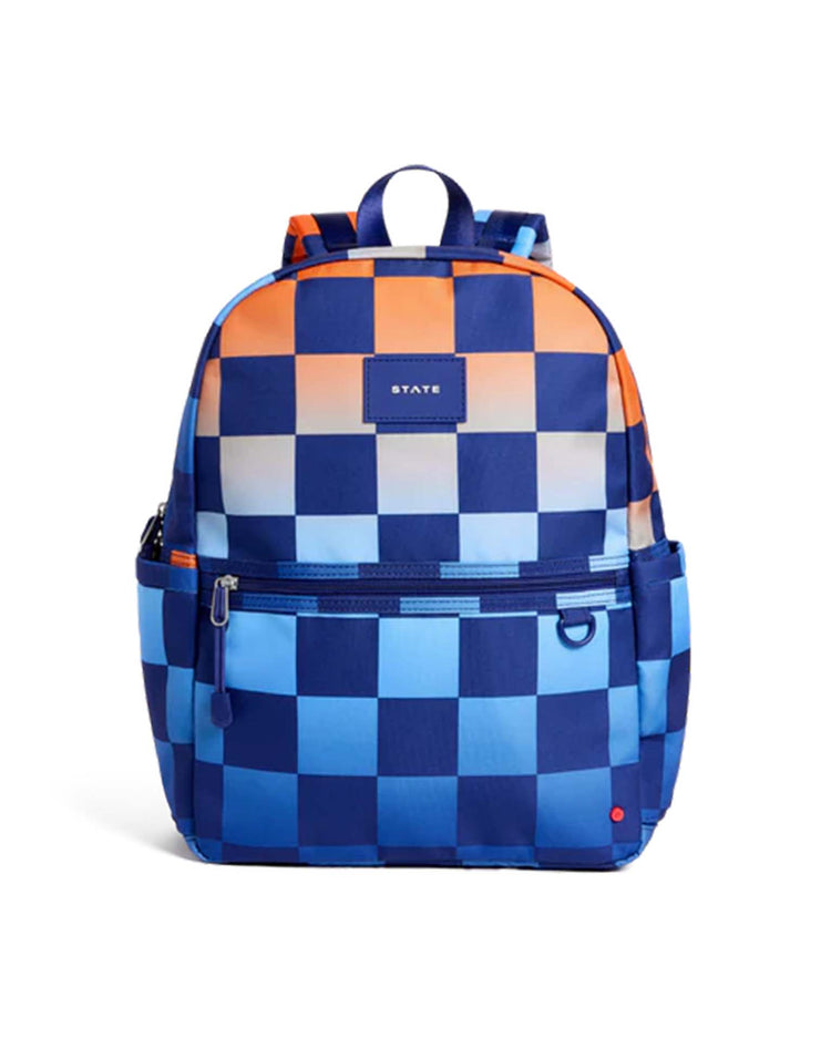 A kids' school backpack from STATE Bags, the Kane Backpack in Gradient Checkerboard, features a blue and orange checkerboard pattern, a front zipper pocket, side pockets, and a top handle. The STATE label on the front highlights its classic style—perfect for daily adventures or school days.