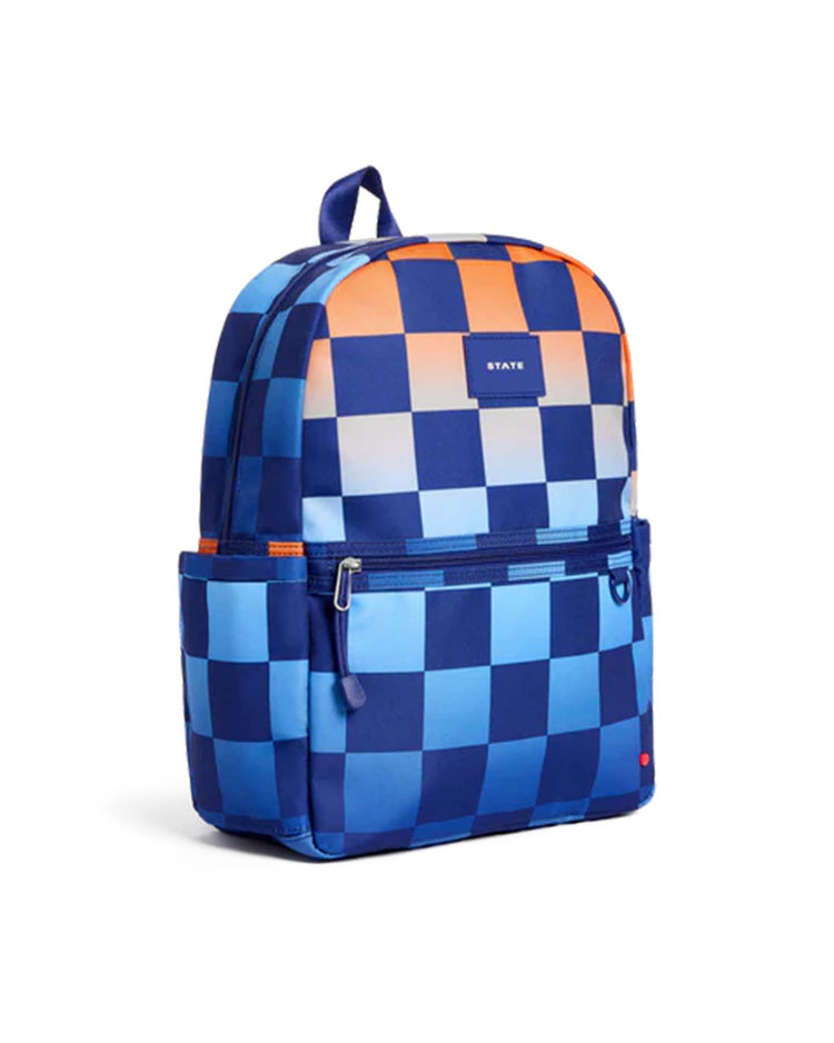 A Kane Backpack in Gradient Checkerboard from State Bags, showcasing a checkered pattern in varying shades of blue and orange, features a front zipper pocket, side pockets, and a small rectangular label on the front—perfect as a stylish school backpack or for weekend adventures.