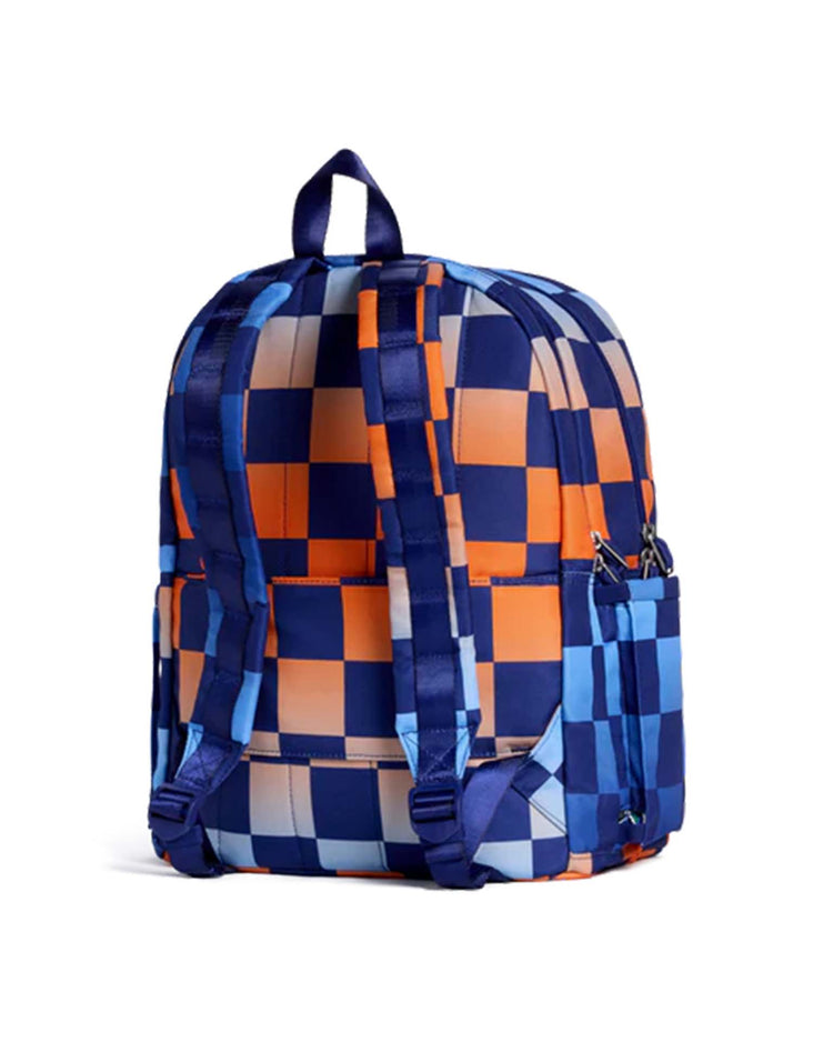 The Kane Double Pocket Backpack in Gradient Checkerboard by STATE Bags features a blue, orange, and light blue checkerboard pattern and is shown from the back with adjustable shoulder straps and a top handle—making it a stylish choice for school.