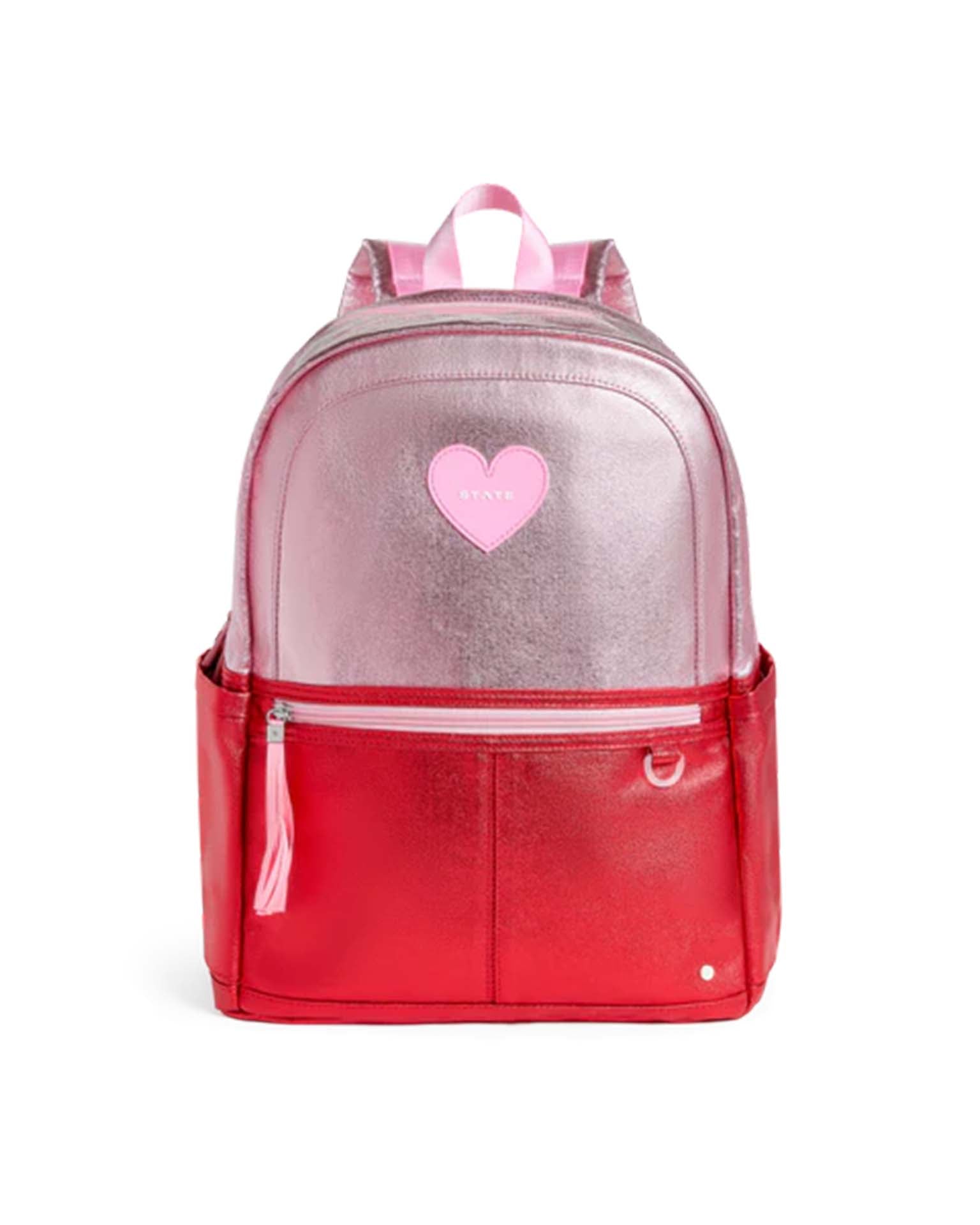The Kane Double Pocket Backpack in pink + red colorblock by State Bags features a shiny metallic pink top half, a vibrant red bottom half, two convenient side pockets, and a playful pink heart patch on the front.