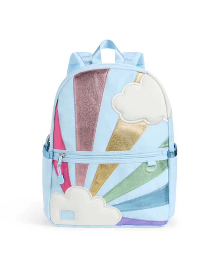 The Kane backpack in Rainbow Cloud by STATE Bags features a light blue design decorated with white cloud patches and vibrant, shimmering rays in pink, gold, blue, green, and purple. This colorful school backpack includes a front zip pocket and matching light blue straps.