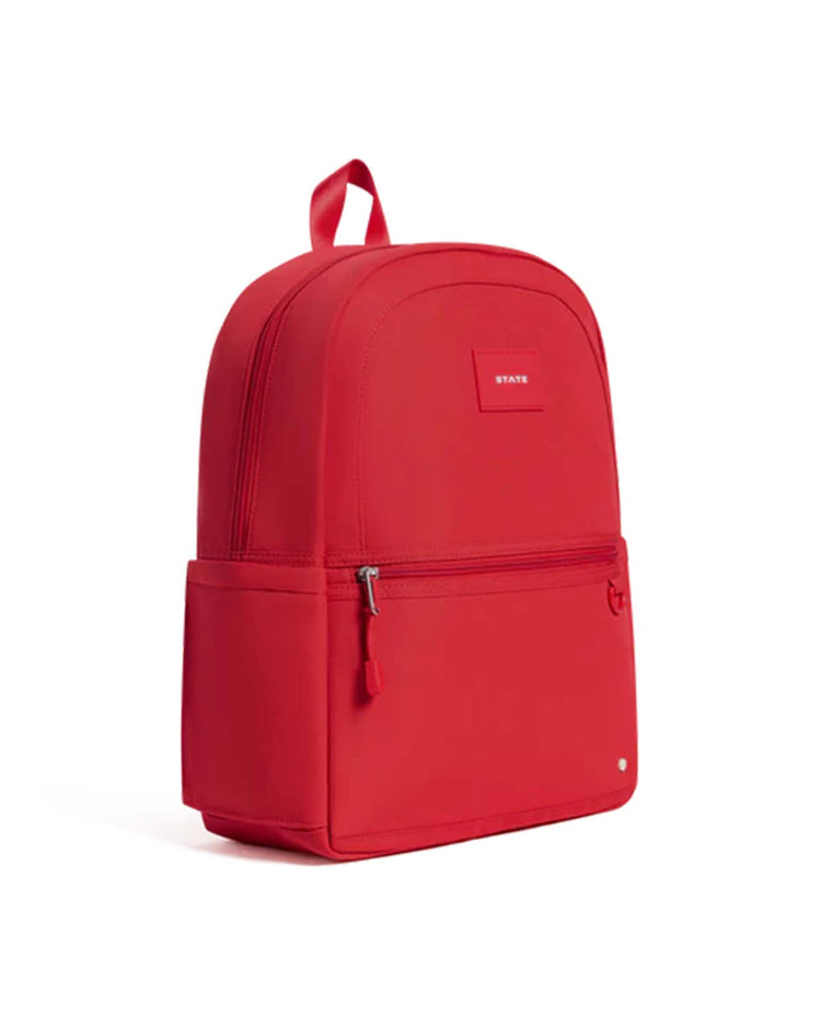 A vibrant red Kane Backpack by STATE Bags, featuring a front zip pocket, side pocket, and top handle, displayed against a plain white background.