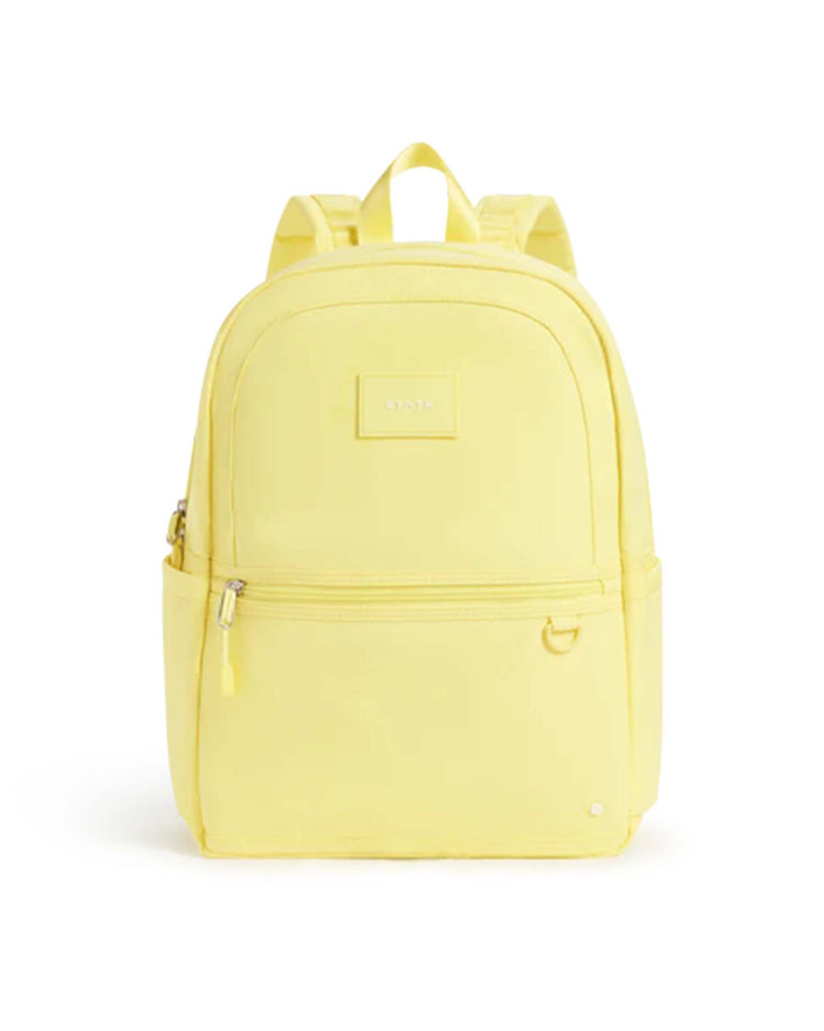 The state bags kane backpack in butter yellow stands upright against a white background, showcasing two zippered compartments, a top handle, side pockets, and adjustable shoulder straps—making it the perfect choice for a stylish travel backpack or a versatile school backpack.