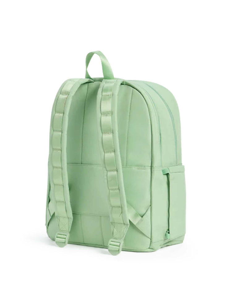 A light green Kane Double Pocket Backpack by STATE Bags stands upright against a plain white background, featuring padded shoulder straps, a top handle, and two side pockets. This stylish STATE Bags backpack is perfect for school.
