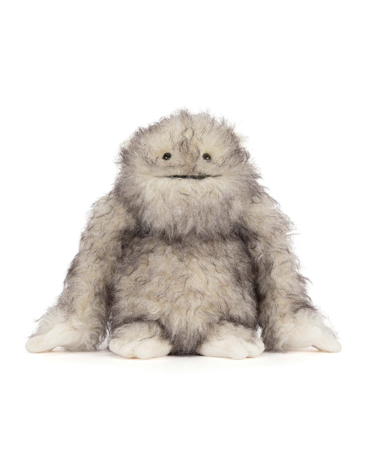 The jellycat bretti yeti is a plush toy with shaggy gray and white fur, round dark eyes, and big white hands and feet. This adorable stuffed animal sits upright against a white background—perfect for any collection.