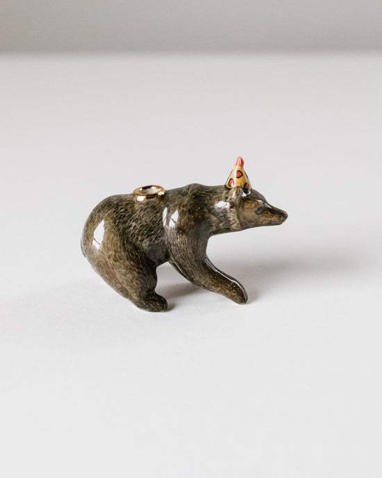 A small figurine of a brown bear cake topper on all fours, crafted in a glossy, metallic finish with a colorful headdress and heirloom-quality craftsmanship by Camp Hollow.