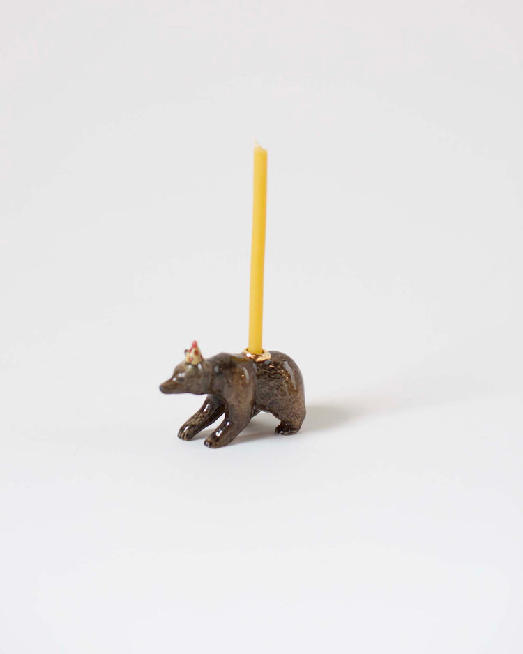 A bronze, heirloom-quality craftsmanship candle holder shaped like a bison with a single yellow candle inserted on its back, set against a white background.