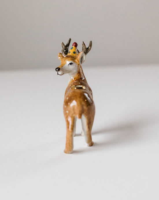 A ceramic figurine of a stag cake topper from Camp Hollow, positioned on a plain white background.