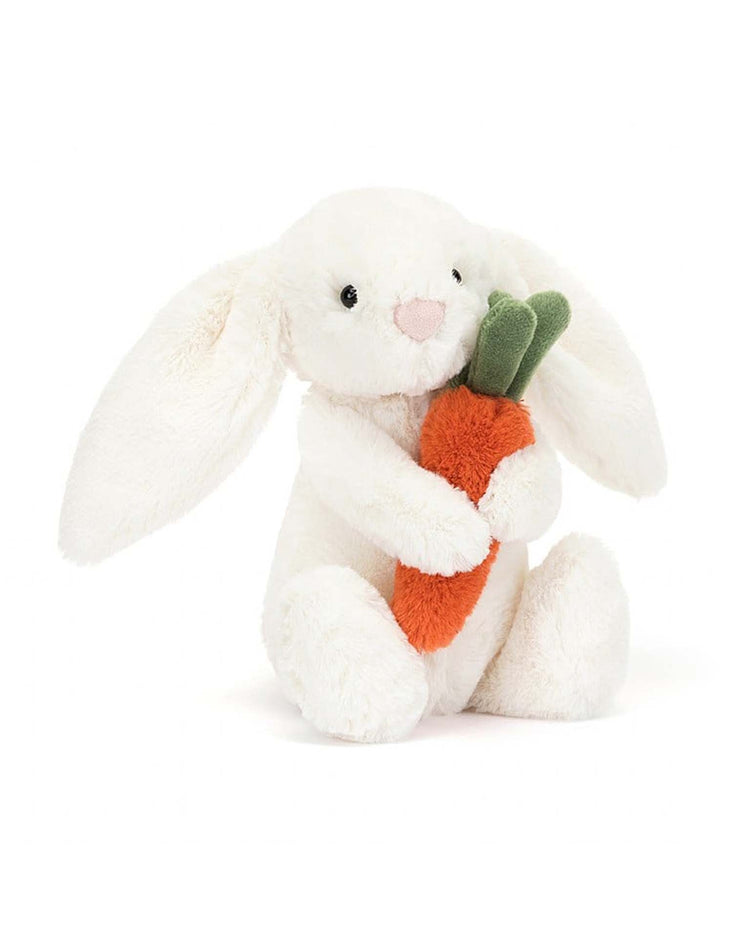 The Bashful Carrot Bunny Little by Jellycat, a plush white bunny holding a bright orange carrot toy, is perfect for cuddles.