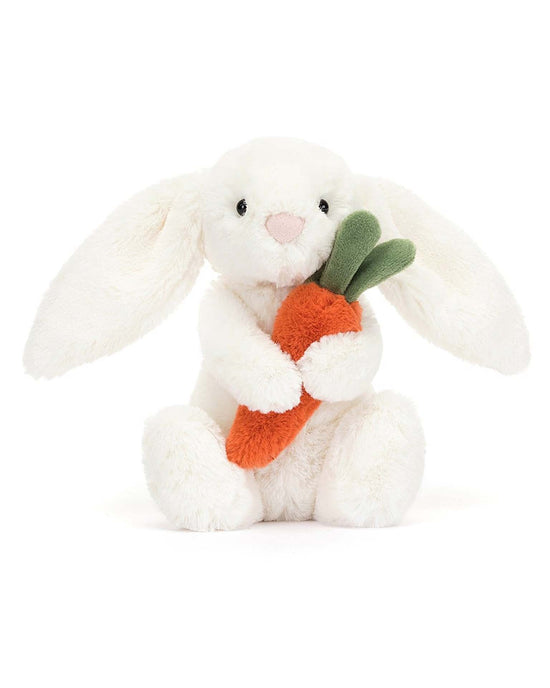The bashful carrot bunny little by jellycat is a white stuffed animal holding an orange carrot toy with green leaves.