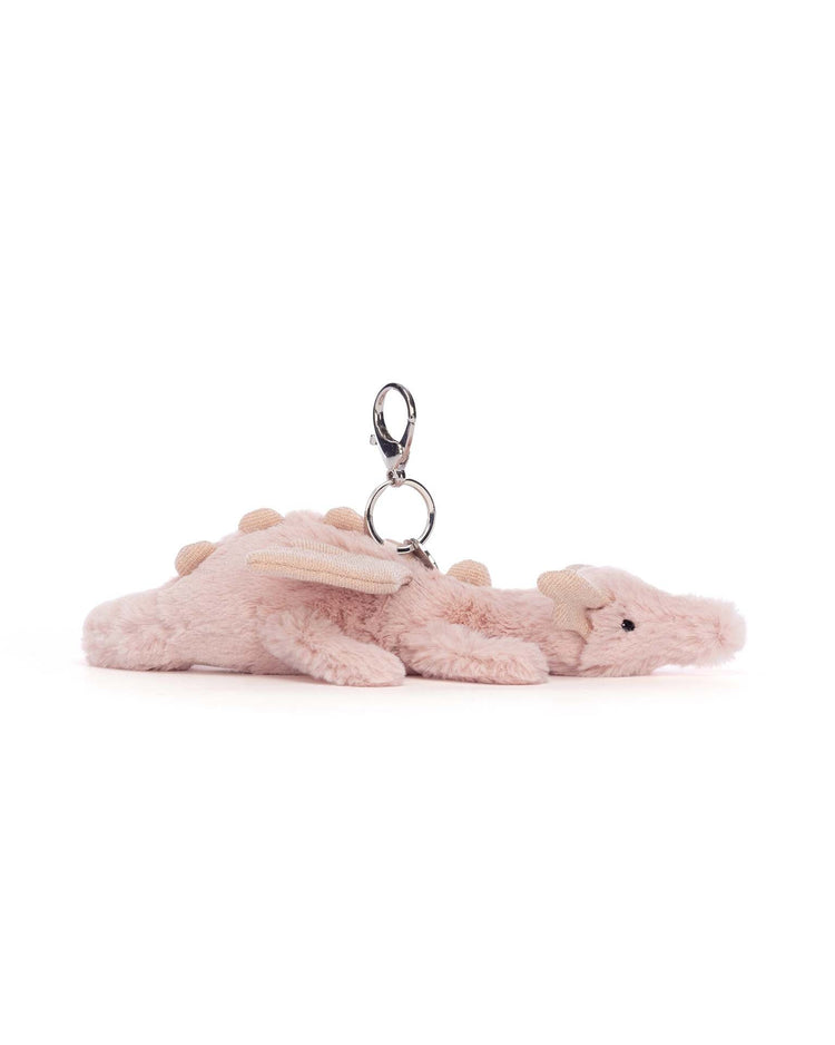A charming Jellycat Rose Dragon Bag Charm featuring glittery wings and small spikes along its back, displayed against a plain white background. Perfect as a whimsical keychain you'll want to carry everywhere.