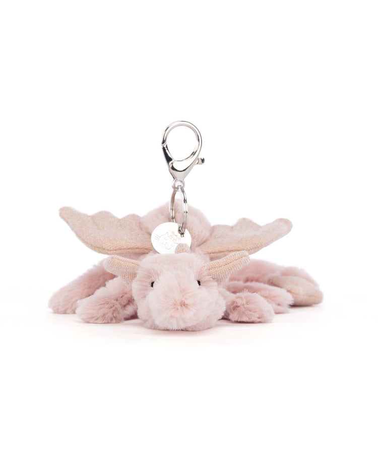 Discover the enchanting Rose Dragon Bag Charm by Jellycat, featuring a soft pale pink dragon design with glittery wings and large horns, complete with a silver clasp attachment. Perfect for adding a whimsical touch to your everyday accessories.