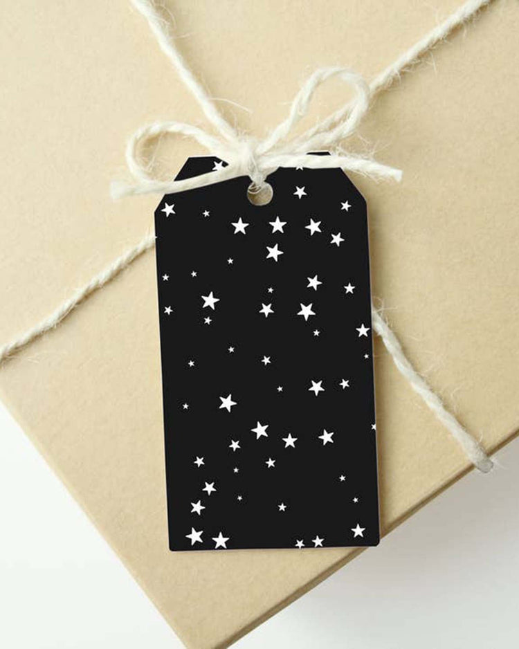 A brown paper package tied with white string features a mellowworks starry night gift tag from the set of 10, adorned with white stars.