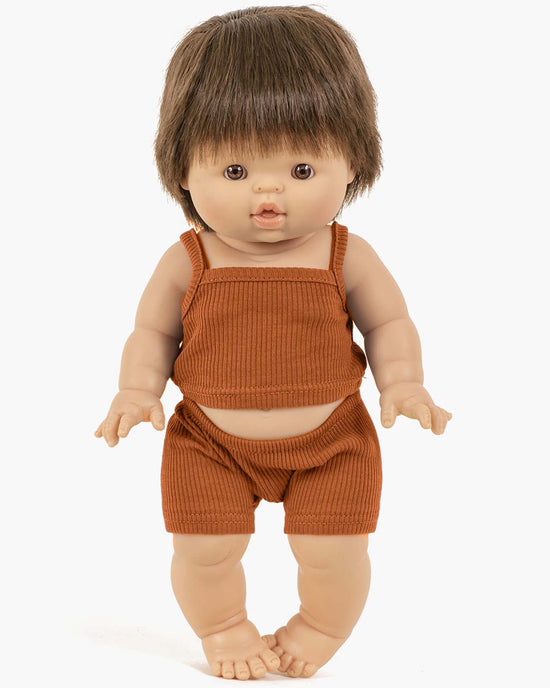 A minikane Paola Reina doll with short brown hair stands upright, wearing the Les P’tits Basiques ribbed tank and short set in cognac, with her arms slightly bent and fingers spread.