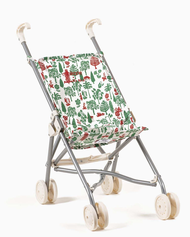 The Nathalie Lété stroller in trees & chaperon by minikane is a foldable toy stroller with a white frame and a seat showcasing a vibrant, nature-themed design. Ideal for timeless dolls like Minikane or Paola Reina, it features four white wheels and white handles.