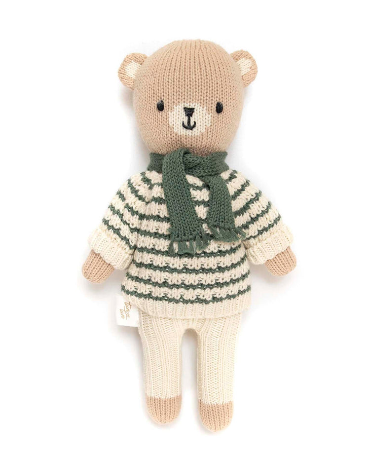 A knitted bear plush toy from tun tun, named "bear striped sweater + scarf in green," features a green and white striped sweater and a matching green scarf, crafted from soft Pima cotton for an heirloom-quality feel.