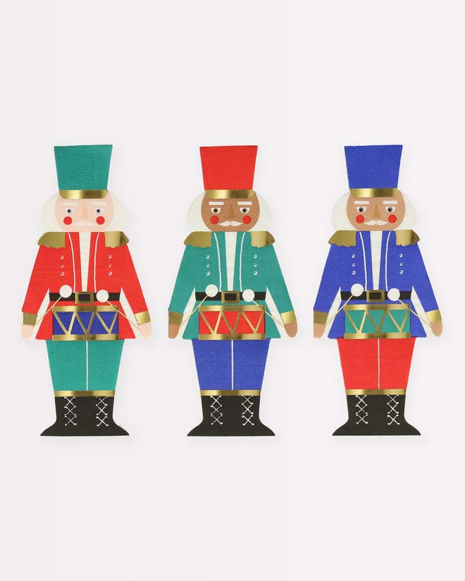 Three meri meri nutcracker napkins with varying hat colors arranged side by side.