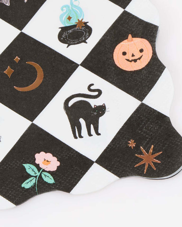 A black and white checkered surface showcases Halloween-themed illustrations—a black cat, cauldron, pumpkin, crescent moon, stars, and a pink flower—making the meri meri patchwork halloween small napkins a charming choice to add festive flair to your table setting. Pair them with copper foil or wavy edge napkins for an extra touch of elegance.