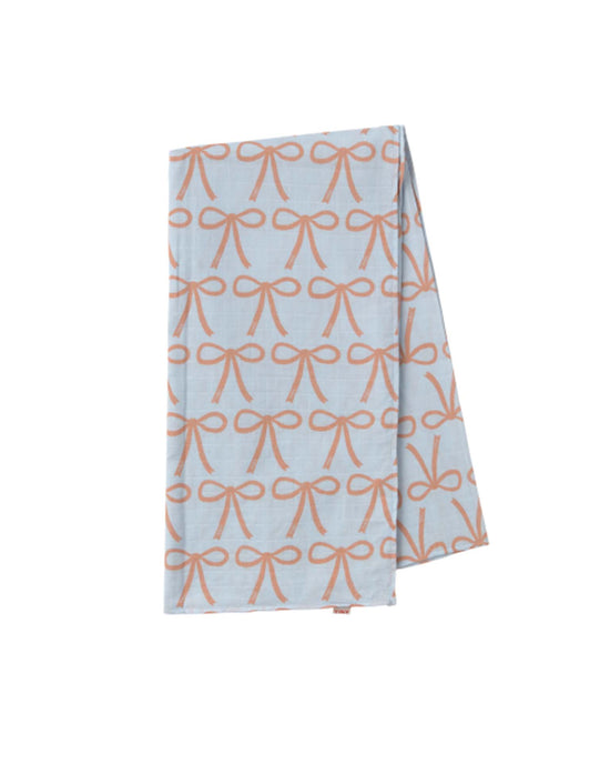 The bows swaddle in light blue from tiny cottons is a folded blue cloth showcasing unique prints with a repeating orange bow pattern, embodying the brand's high-quality style.