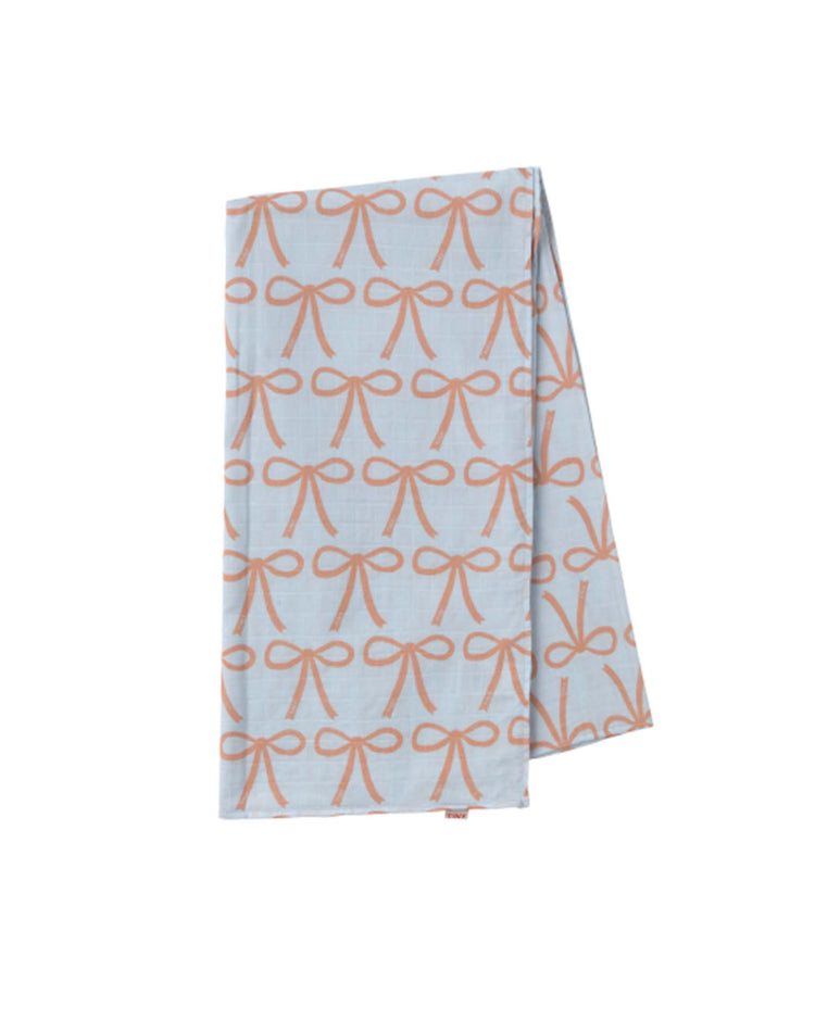 The bows swaddle in light blue from tiny cottons is a folded blue cloth showcasing unique prints with a repeating orange bow pattern, embodying the brand's high-quality style.