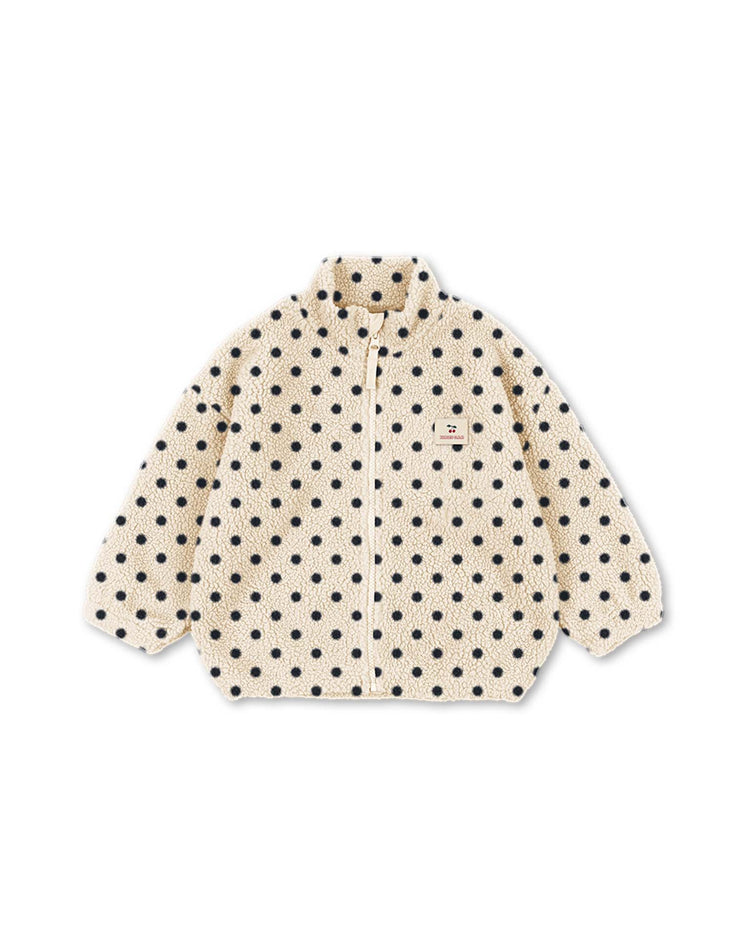The "jody embroidery teddy jacket in dot lumiere" by konges sløjd features a beige, pile fleece design with black polka dots, front zipper, long sleeves, and a small rectangular patch on the left chest. Crafted from recycled polyester and OEKO-TEX certified materials, this jacket offers a soft, textured look and a relaxed fit.