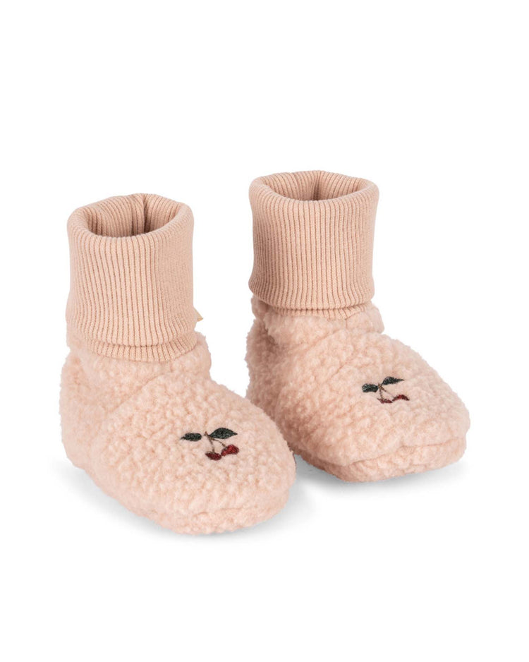 Safa boots in rose smoke by konges sløjd—soft pink baby booties crafted from recycled polyester with a cozy fleece texture, ribbed knit cuffs, and an embroidered animal face on the toes, shown on a white background.