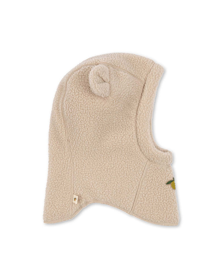 The safa helmet in oxford tan by konges sløjd is a beige fleece balaclava for children, featuring a small round ear on top and designed for warmth and comfort. This hat has a soft texture and offers full coverage for the head and neck.