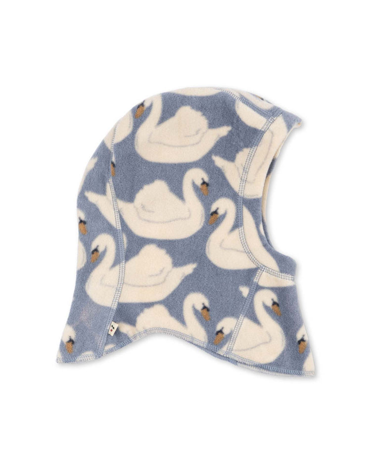 The tavi fleece balaclava in swan by konges sløjd (KS105772) is a blue balaclava featuring a repeating pattern of white swans with orange beaks, displayed on a white background.