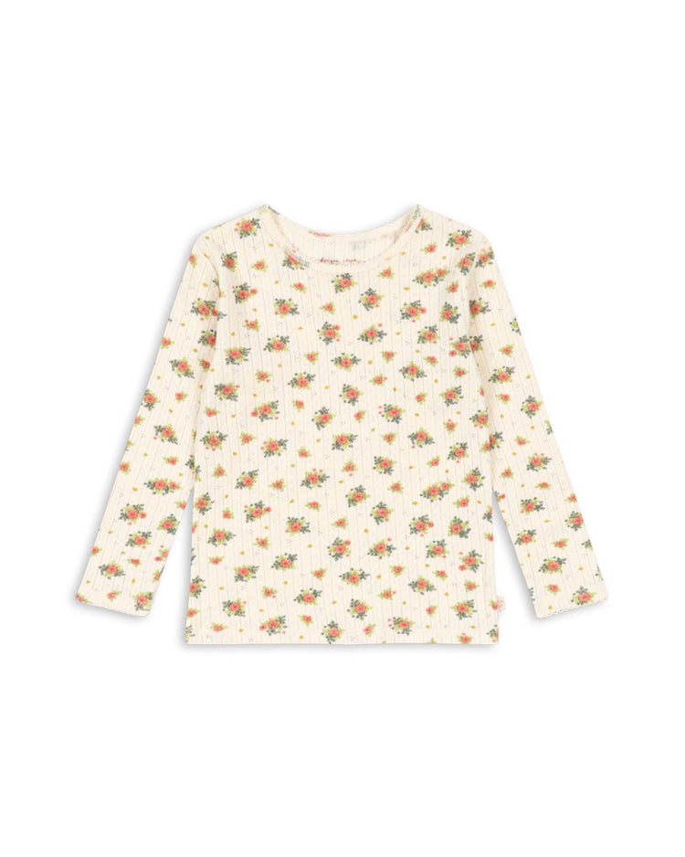The minnie blouse in rosetto by konges sløjd is a cream-colored, long sleeve organic cotton blouse featuring a ribbed texture and a delicate floral print in red, orange, and green. GOTS certified, this shirt is displayed laid flat on a white background.