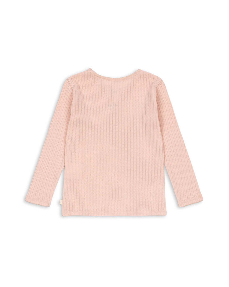 The minnie blouse in pale blush by konges sløjd, a long-sleeve ribbed knit shirt made from GOTS certified organic cotton, is displayed flat on a white background with the back side facing up. This blouse serves as an ideal soft base layer for everyday comfort.
