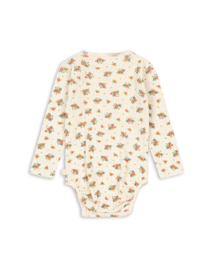 The minnie bodysuit in rosetto by konges sløjd is a long-sleeve baby onesie featuring a cream background with a delicate floral print in pink, orange, and green. Made from GOTS certified organic cotton with a subtle ribbed texture, this essential piece is shown from the back in the image.