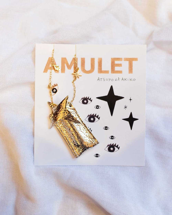 Gold-toned, handmade necklace displayed on a card labeled "ATSUYO ET AKIKO Amulet Crystal Necklace" with decorative graphics, made in the USA.