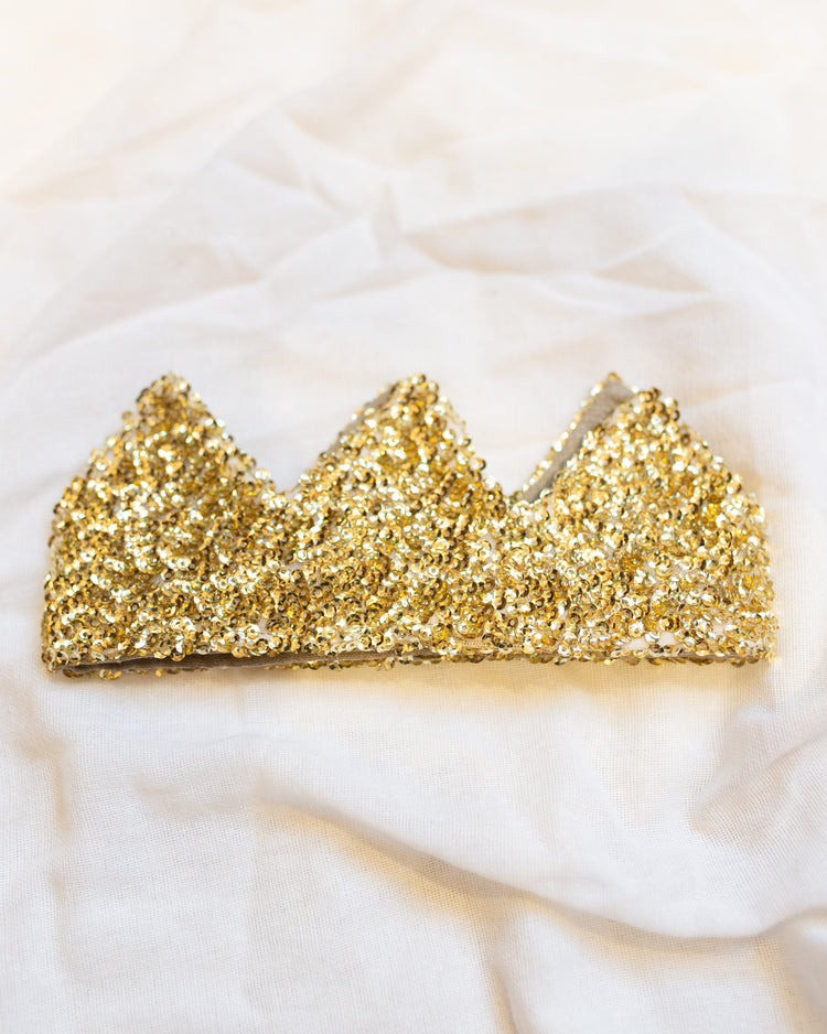 A golden sequined, handmade rocky headband in gold on a light fabric background by Atsuyo et Akiko.