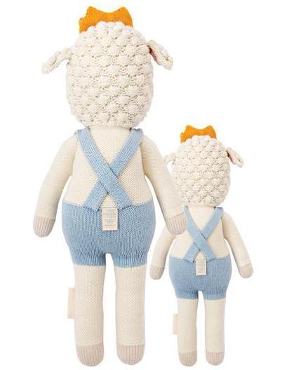 Two knitted dolls with blue overalls, modeled after Sebastian and the little prince, standing back-to-back.