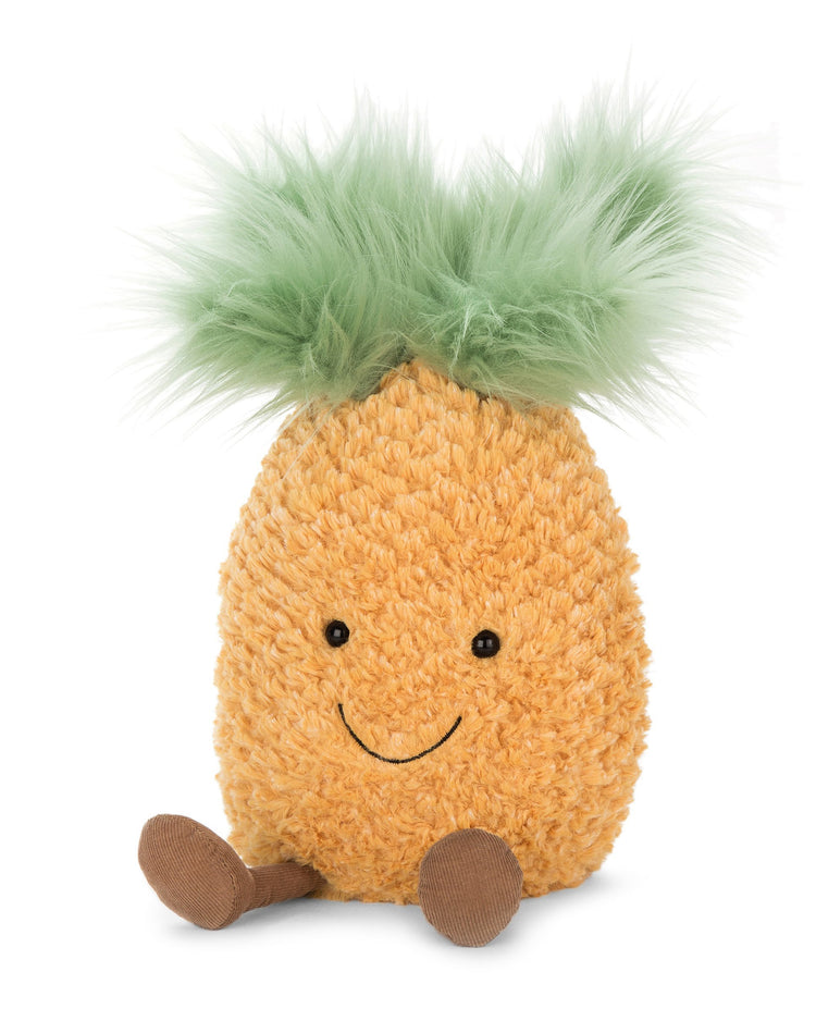 A medium Amuseables Pineapple by Jellycat with green hair sitting on a white background, evoking tropical giggles.