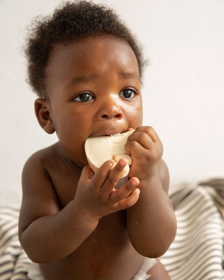 A baby teething on a oli + carol manolo the mushroom toy.