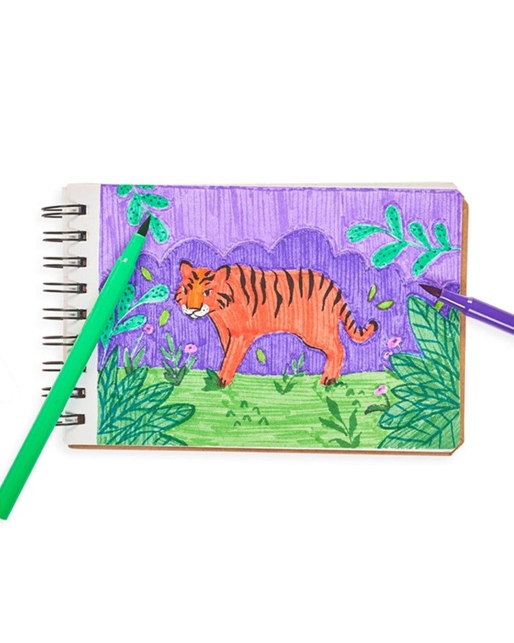 A hand-drawn sketch of a tiger on a spiral notebook with ooly brilliant brush markers set of 12 featuring vibrant colors.