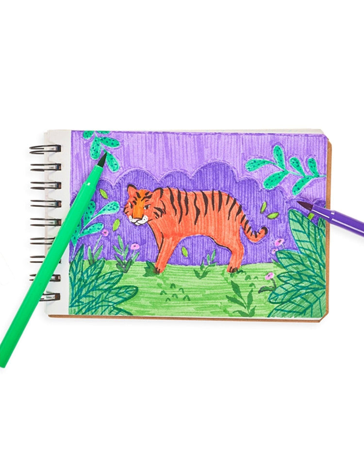 A hand-drawn sketch of a tiger on a spiral notebook with ooly brilliant brush markers set of 12 featuring vibrant colors.
