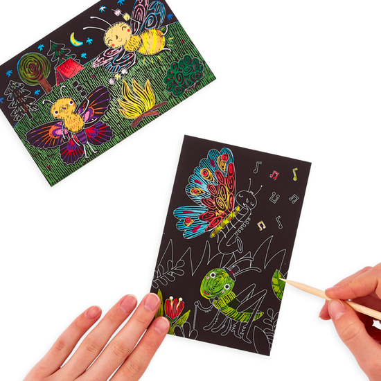 A hand holding a Ooly mini scratch & scribble art kit: bug buddies - 7 piece set with a drawing of a butterfly on it.