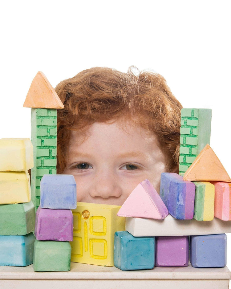 Child peeking over a colorful carrie's castle sidewalk chalk made of geometric pieces by twee.