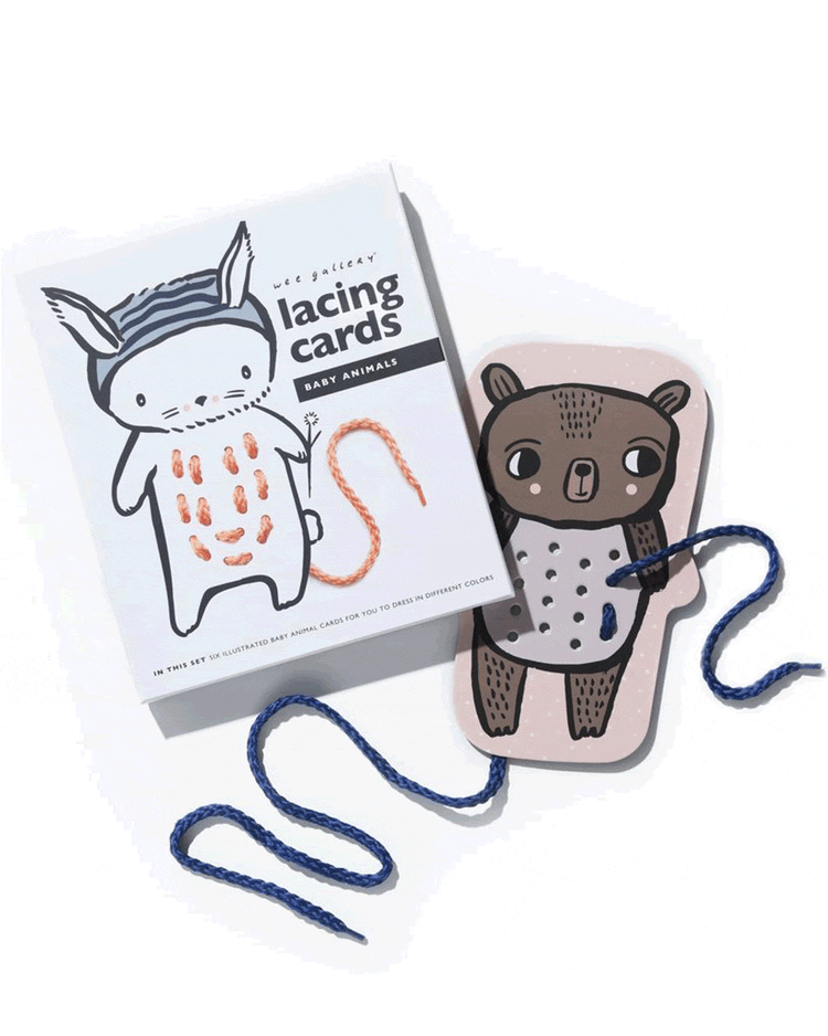 A set of Wee Gallery baby animal lacing cards with a string threaded through holes on a bear card.